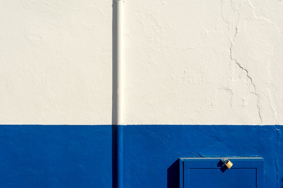 Minimalist abstract style photograph of white and blue wall with a padlock.